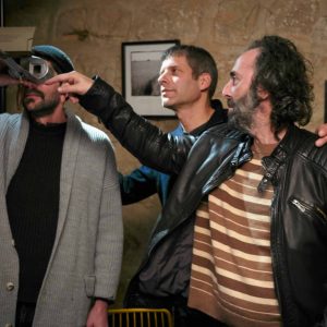 Close-up of three men engaging with stereographic camera at art gallery.